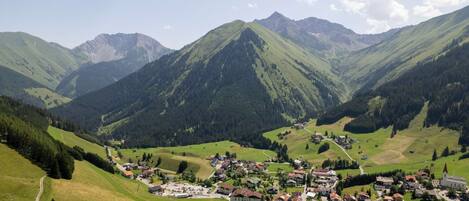 A mountainous village with a central church, surrounded by lush green hills and a clear sky.