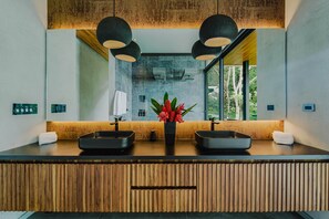 A modern bathroom with a wooden vanity, two black sinks, and a large mirror.