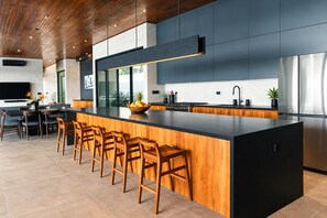 A modern kitchen with a central island, bar stools, and a stainless steel refrigerator.