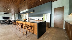 A modern kitchen with a central island, bar stools, and a dining area.