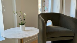 Een moderne woonkamer met een ronde marmeren tafel, een donkergrijze bank en een potorkidee.