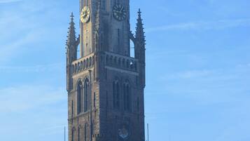 A historic tower with a clock, gothic architecture, and a spire in the background.