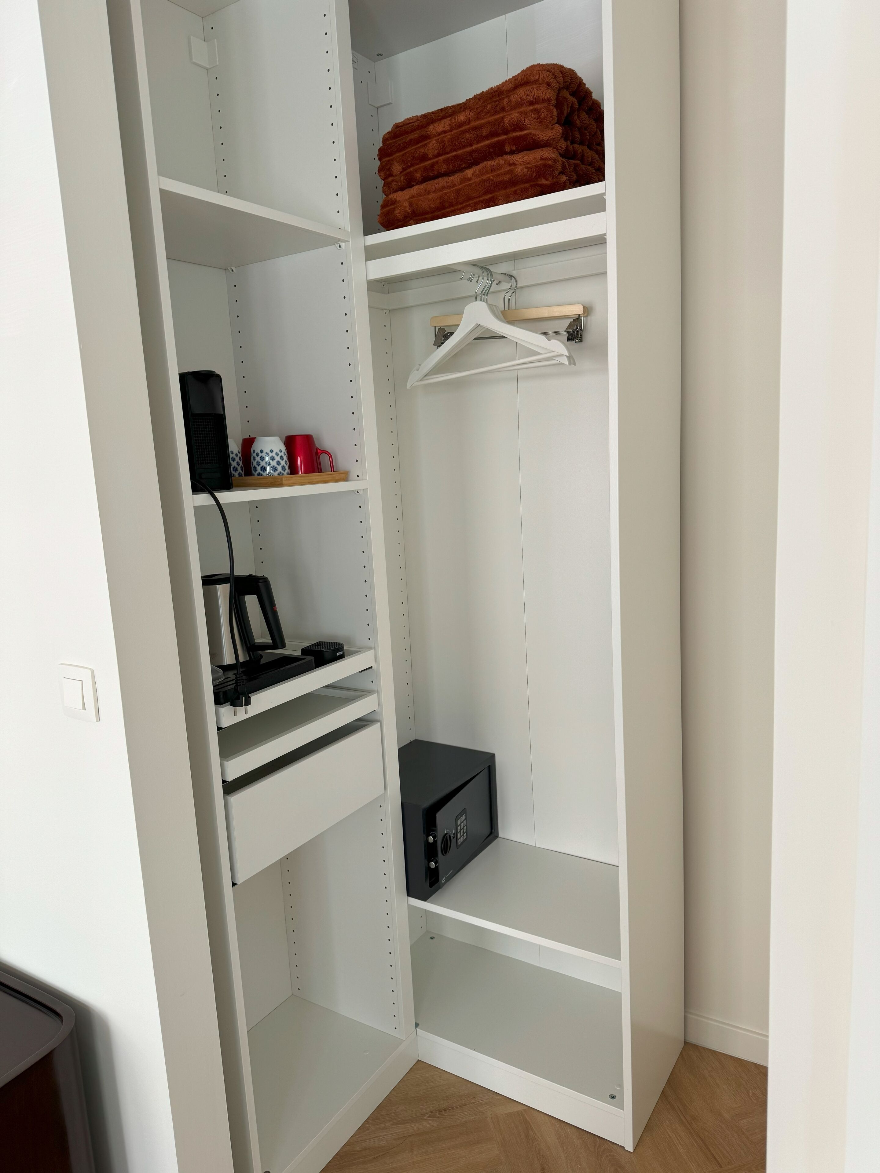 A walk-in closet with open shelves, a hanging rod, and a safe.