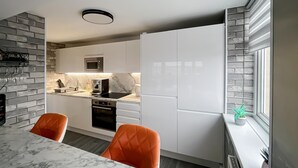 Eine moderne Küche mit weißen Schränken, einer Marmorarbeitsplatte und einem eingebauten Backofen.