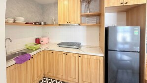A kitchen with wooden cabinets, a stainless steel refrigerator, and a tiled backsplash.