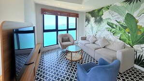 A modern living room with a large window, a sofa, a chair, and a television.