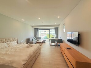 Habitación de hotel con cama, sofá, televisión y zona de comedor con sillas y mesa.