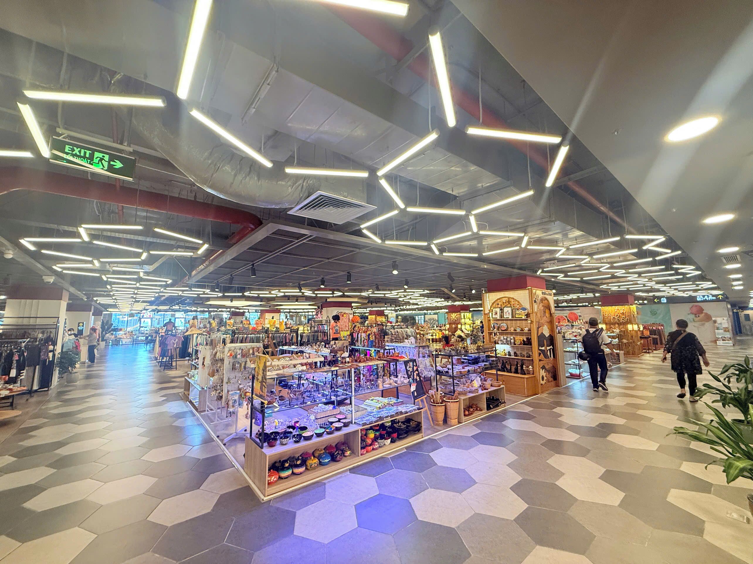 A spacious indoor market with hexagonal patterned flooring and modern lighting fixtures.