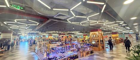 A spacious indoor market with hexagonal patterned flooring and modern lighting fixtures.