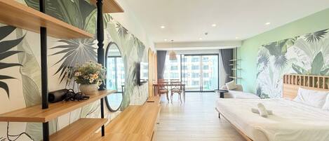 A modern hotel room with a bed, wooden shelves, a dining area, and a large window.