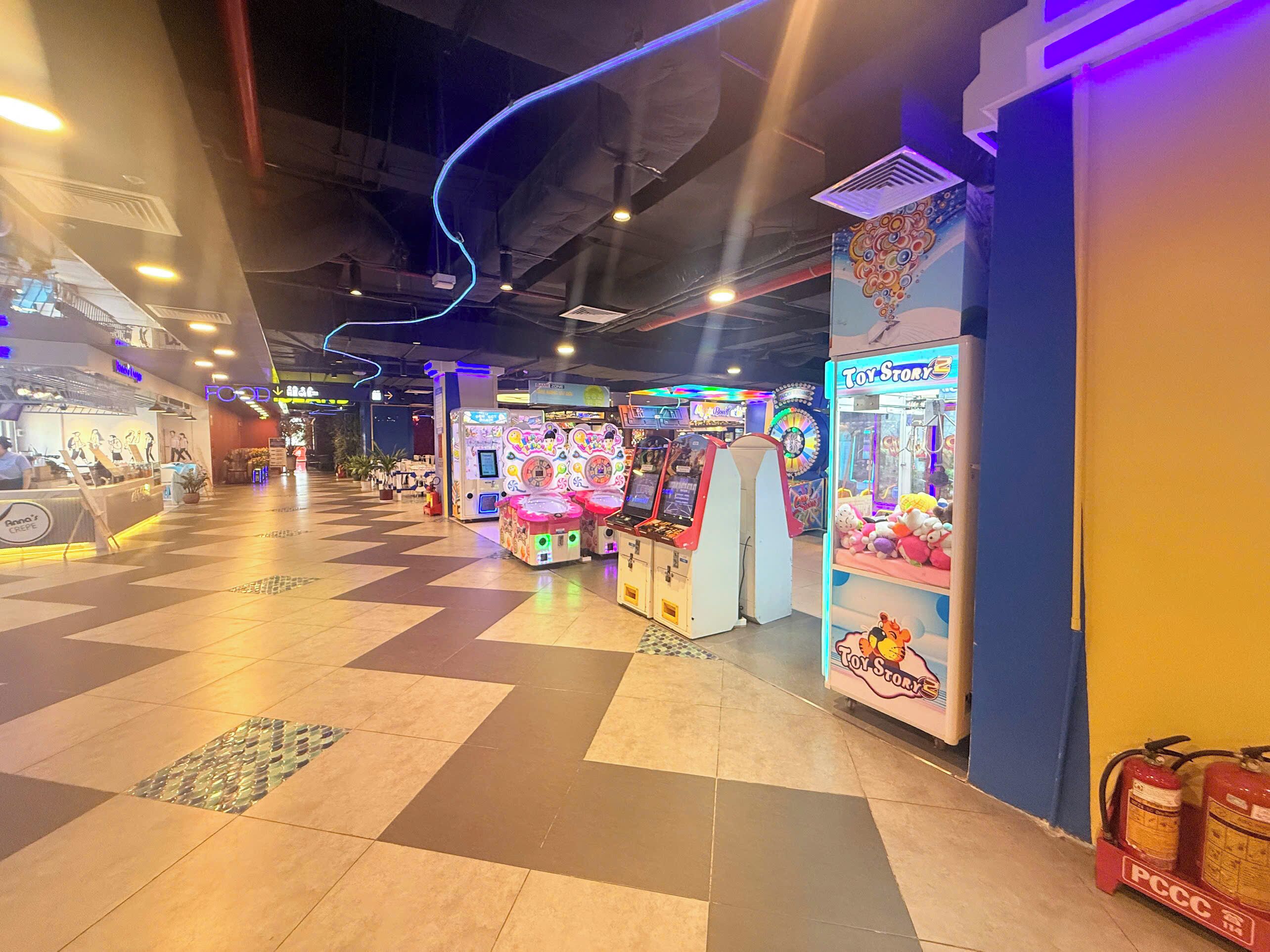 Een overdekte speelhal met grijpmachines en een foodcourt.