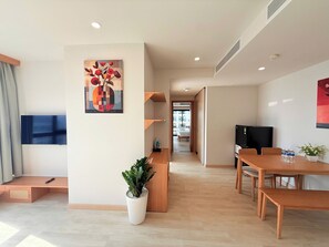Una sala moderna con comedor, televisor y una planta en maceta.