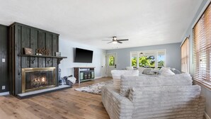 Ein Wohnzimmer mit Kamin, einer Couch und einem an der Wand befestigten Fernseher.
