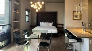 Une chambre d’hôtel moderne dotée d’un grand lit, d’une table à manger en verre et d’un coin cuisine.