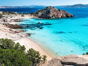 A coastal landscape with a sandy beach, clear turquoise waters, and rocky terrain. - Bright Flat Near the Beaches of Lu Bagnu (Castelsardo)
