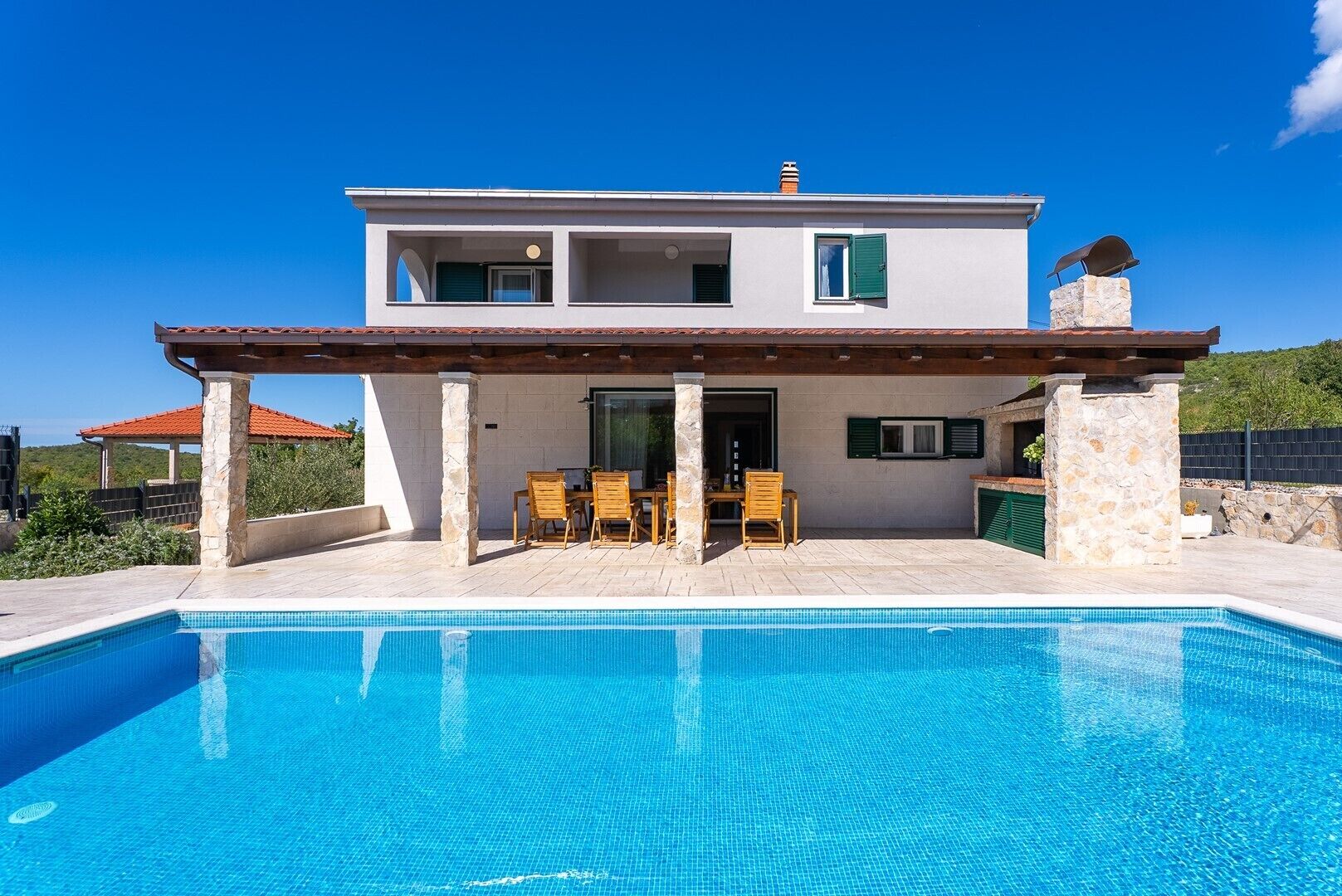 Ein zweistöckiges Haus mit einem Pool davor.