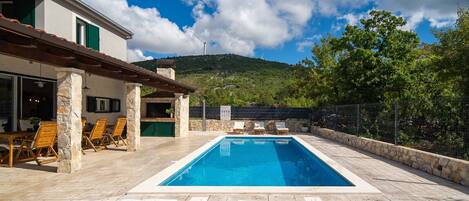 A swimming pool with lounge chairs and a stone wall.