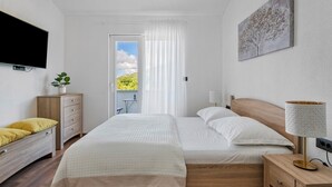 A modern bedroom with a bed, bedside tables, a TV, and a balcony with a view. - **Villa Admiral: Your Idyllic Retreat in rural area of Trogir hinterland** (Blizna Gornja)