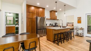 Une cuisine moderne avec des meubles en bois, un réfrigérateur en acier inoxydable et un îlot central doté de tabourets de bar.