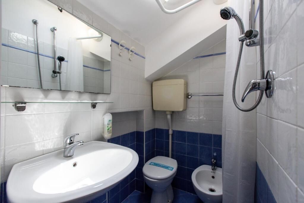 Ein Badezimmer mit einem weißen Waschbecken, einer Toilette, einem Bidet und einer Dusche.