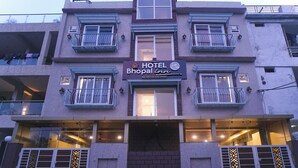 A multi-story hotel building with balconies, a sign for 'HOTEL Bhopal Inn by TEN ON TEN STAYS', and a brick entrance. - Bhopal Inn by Ten On Ten Stays (Bhopal)