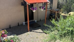A house with a porch, a door, a small garden area with gravel, and hanging flower baskets. - Wonderful studio with WiFi in charming Pecos (Pecos)