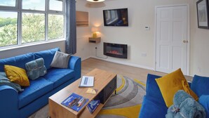 Un salon moderne avec un canapé bleu, une table basse en bois et un téléviseur à écran plat fixé au mur.