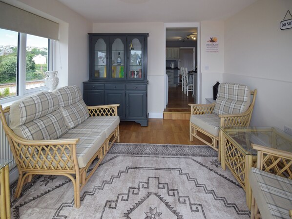 A living room with a sofa, armchairs, a glass coffee table, and a dark blue cabinet with glass doors.