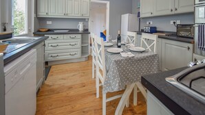 Une cuisine compacte avec des meubles blancs, une table à manger pour deux personnes et un plancher en bois.