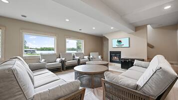 A spacious living room with a fireplace, large windows, and a sign for Sandbar Resort.