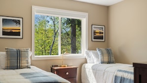 A bedroom with two beds, a nightstand, a window with a view of trees, and framed pictures on the wall. - Sauna| Garage Golf Games| Close to shopping (Pequot Lakes)