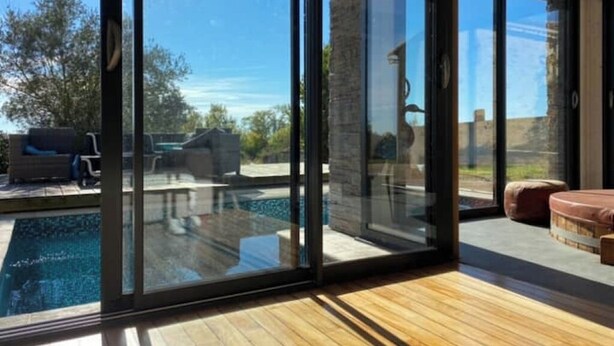 A modern room with large sliding glass doors leading to a pool area. - Exceptional eco-domain (spa&pool) (Le retail)