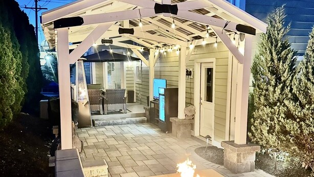 A covered patio area with a fire feature, outdoor seating, and a television. - The Sand Trap 3 bed 3 bath new development walkable to Oakmont country club (Oakmont)