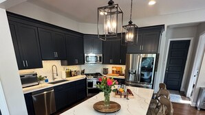 A modern kitchen with dark cabinets, a white marble island, and a wooden bench. - The Sand Trap 3 bed 3 bath new development walkable to Oakmont country club (Oakmont)