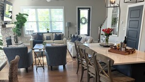 A spacious living area with a fireplace, a dining table with chairs, and a kitchen area with a refrigerator. - The Sand Trap 3 bed 3 bath new development walkable to Oakmont country club (Oakmont)