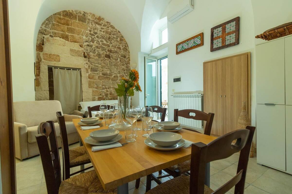 A dining area with a stone wall, wooden table, and chairs.