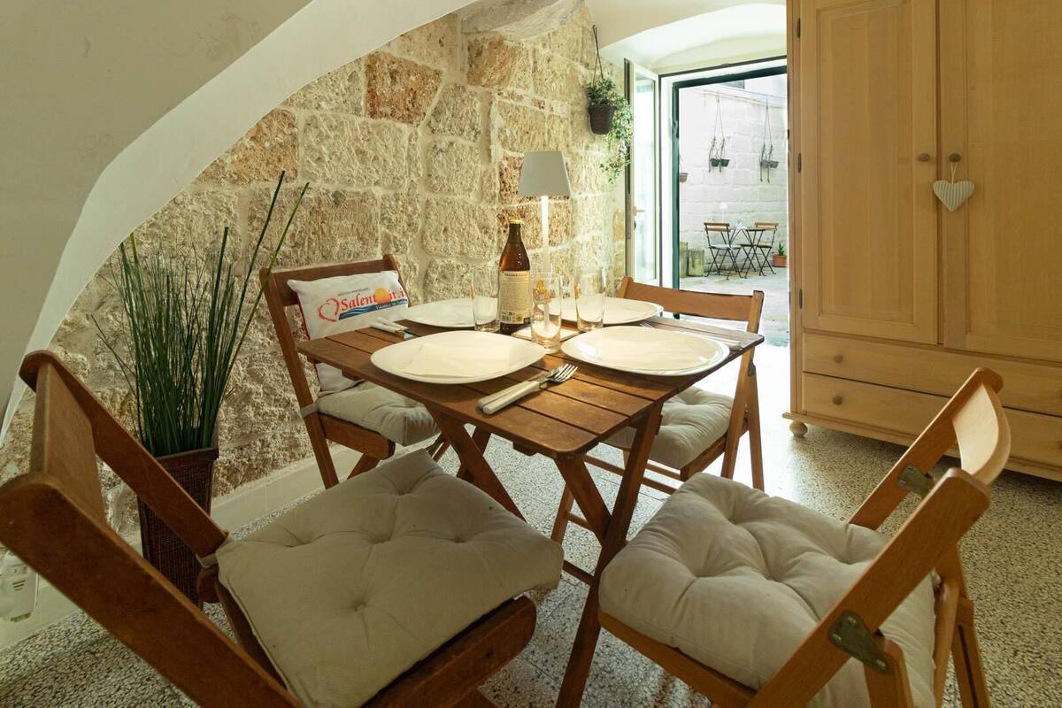A cozy dining area with a stone wall, wooden furniture, and a view of the outside.