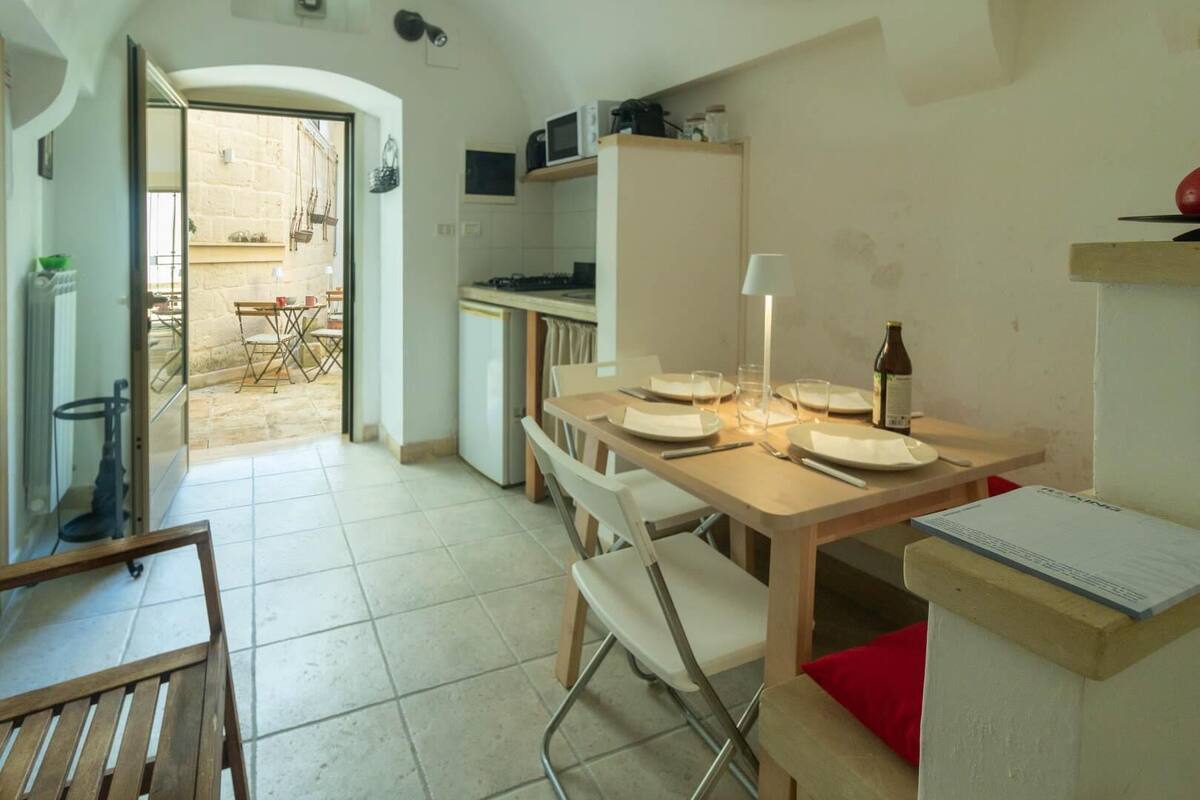 A compact kitchen with a dining area, a refrigerator, a microwave, and a table set for two.