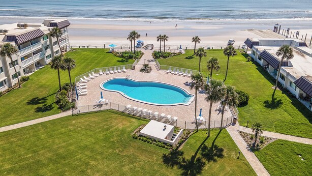 A resort with a swimming pool, beach access, and palm trees.