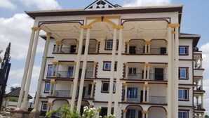Un immeuble à plusieurs étages doté de balcons, d’une entrée centrale et d’une façade symétrique.