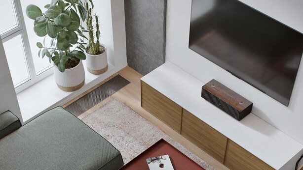 Un salon moderne avec un canapé d’angle, une table basse et un téléviseur fixé au mur.