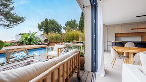 Un espace de vie extérieur moderne comprenant une piscine, une terrasse en bois et un coin repas avec une table et des chaises.