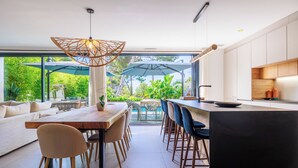 Une cuisine moderne avec un coin repas, de grandes fenêtres et une vue sur la verdure.