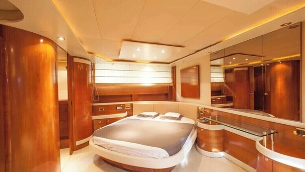 Een luxueuze slaapkamer met een groot bed, houten lambrisering, een glazen make-up tafel en een grote spiegel.