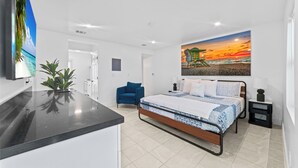 Ein modernes Schlafzimmer mit Bett, Schreibtisch, Stuhl und einem Abendsonnenbild.