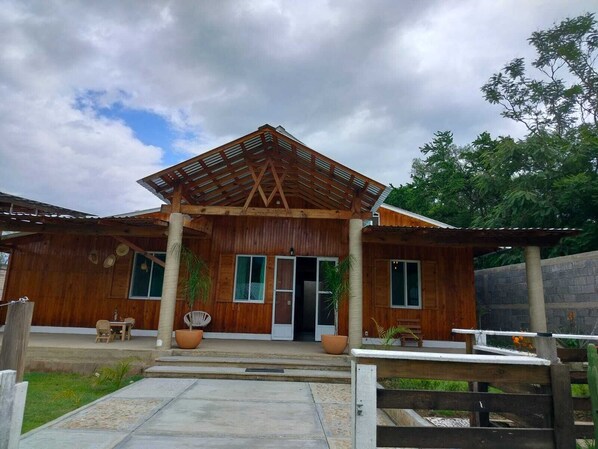 A wooden building with a covered entrance, large windows, and potted plants. - Punta Paraíso Oaxaca (Oaxaca)