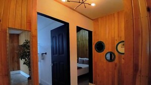 A hallway with wooden walls, a door leading to a bedroom, and a ceiling light fixture. - Punta Paraíso Oaxaca (Oaxaca)