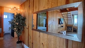 A wooden interior with a large mirror reflecting a staircase and a small seating area. - Punta Paraíso Oaxaca (Oaxaca)