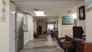 A spacious living room with a modern kitchen, a dining area, and a seating area with a leather chair. - Fishermans Cottage (Withernsea)