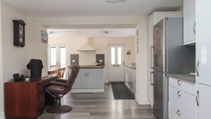 A modern kitchen with a dining area, wooden flooring, and a ceiling fan. - Fishermans Cottage (Withernsea)